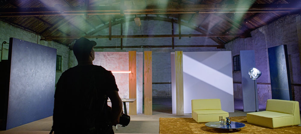 Video Caparol Trendfarbe 2025 Cosmic Light Lavendel 105 mit Mann von Hinten in modernen Wohnzimmer mit Nordlichtern an der Decke.